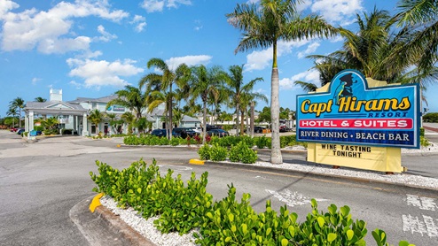 Capt. Hiram's Resort entrance featuring a colorful sign, palm trees, and a welcoming atmosphere for guests and diners.