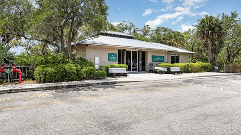 A modern building labeled "Environmental Learning Center" surrounded by greenery and benches, under a partly cloudy sky.