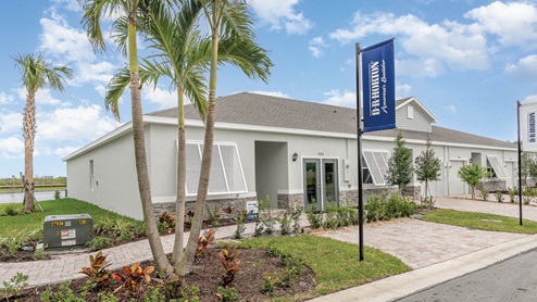 Modern single-story home with stone accents, surrounded by palm trees and lush landscaping, featuring a welcoming front entrance.