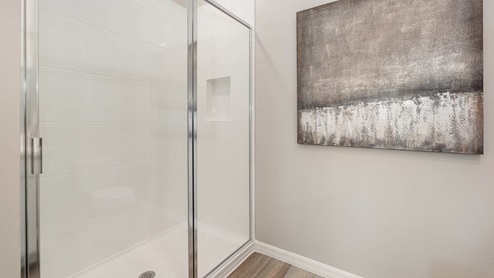 Modern bathroom featuring a glass shower with white tiles and a large abstract painting in muted tones on the wall.