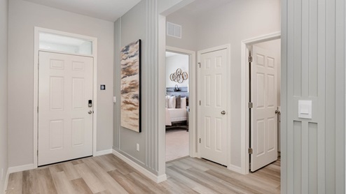 Entry door with light coastal decor, wood panel on walls and vinyl flooring