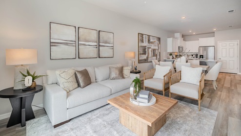 Open floorplan with living room, dining room and kitchen. Light beige and gray tones in decor. Vinyl plank flooring and white couch