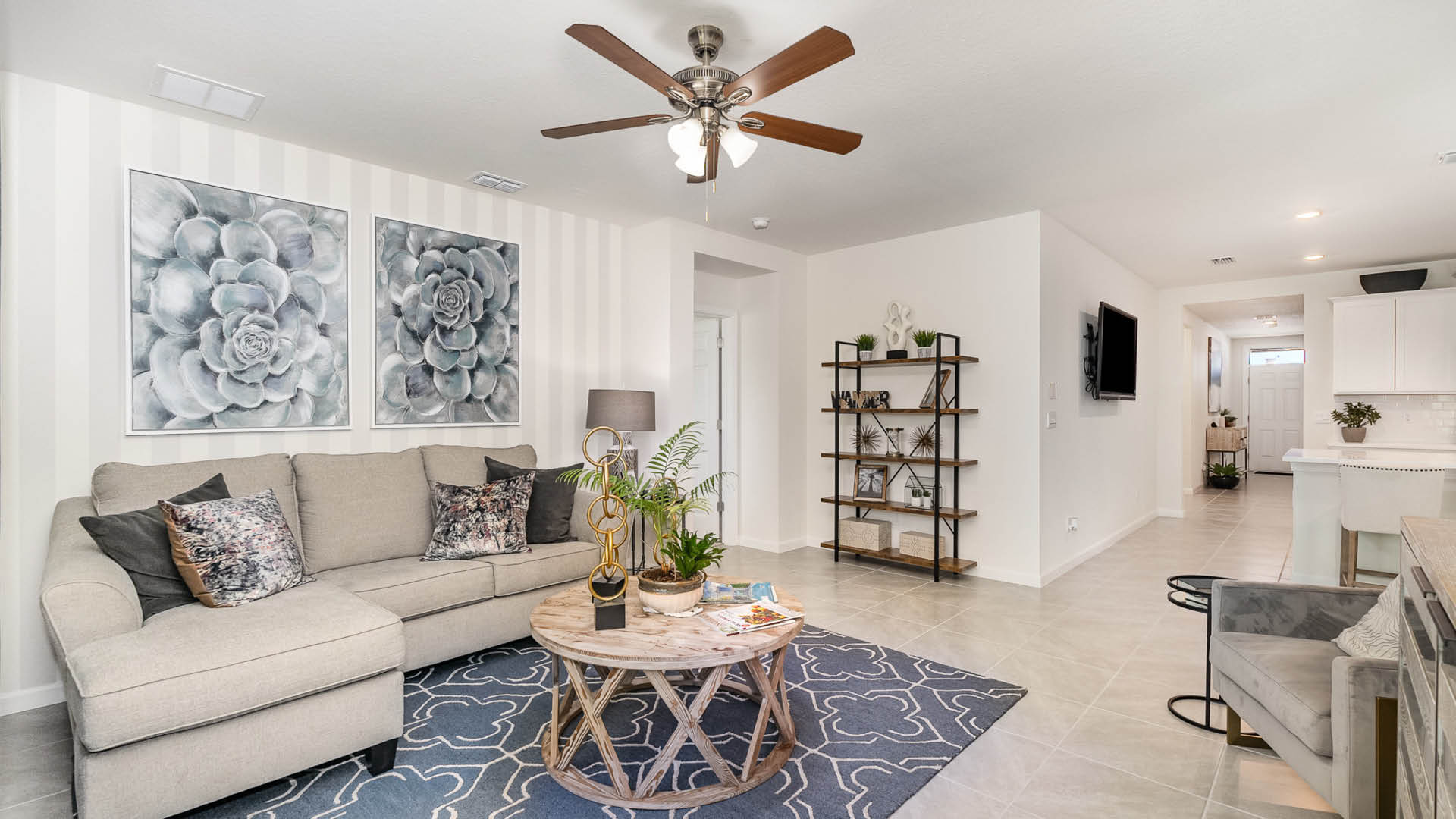 Bright living room featuring a beige sectional sofa, round wooden coffee table, and stylish decor with wall art and a bookshelf.