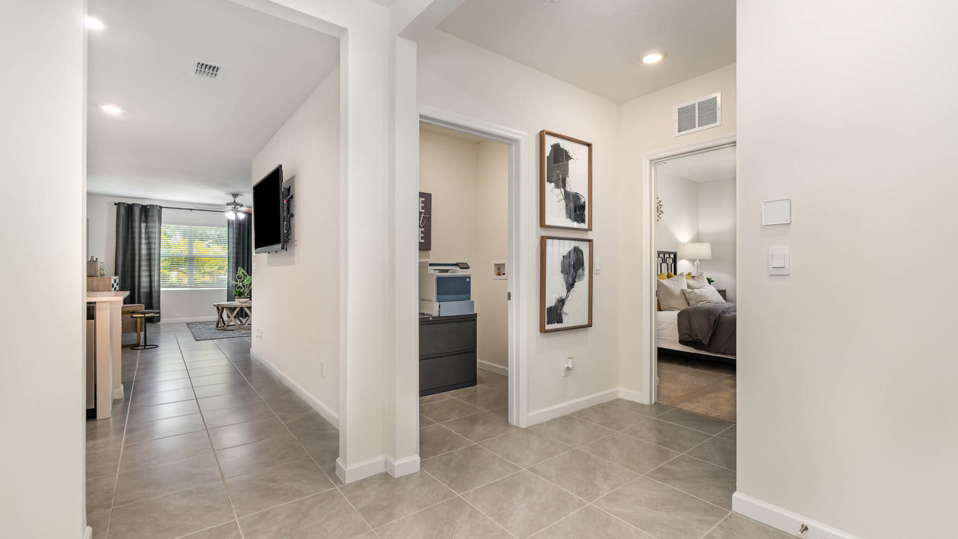 Modern hallway with beige tiles, leading to a cozy living area with a window, and an open bedroom door in the background.