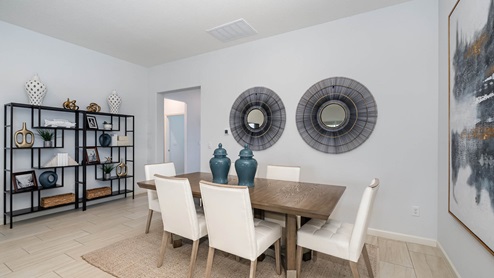 A modern dining area featuring a wooden table, white chairs, decorative mirrors, and stylish shelves with decor items.