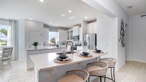 Bright, modern kitchen featuring white cabinetry, stainless steel appliances, and a stylish breakfast bar with woven seats.