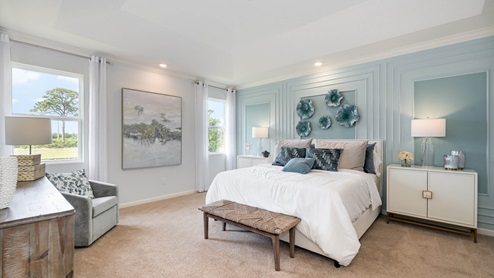 Bright, airy bedroom featuring a white bed with teal accents, decorative wall art, and large windows with sheer curtains.