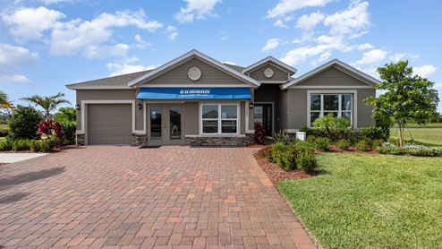 A modern single-family home with a blue awning, stone accents and paver driveway.