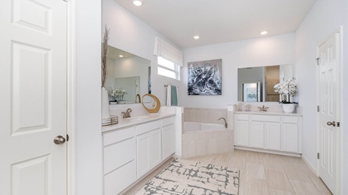 Bright, modern bathroom featuring dual sinks, a soaking tub, large mirrors, and decorative accents with neutral tones and floral elements.