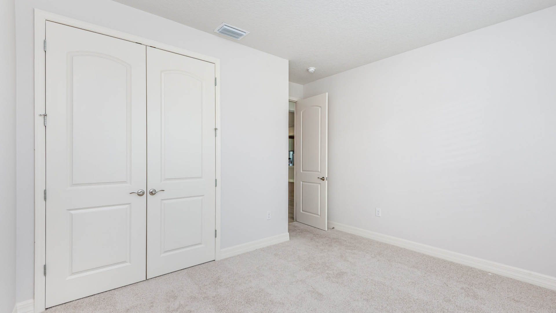 A bright white room featuring two closets and a door, creating a clean and spacious atmosphere.