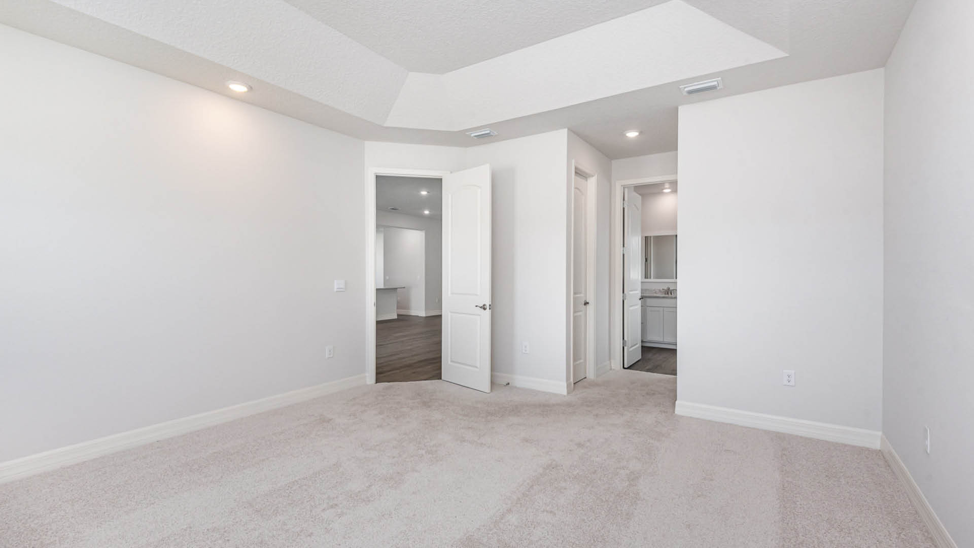 A vacant room featuring plain white walls and a soft white carpet.