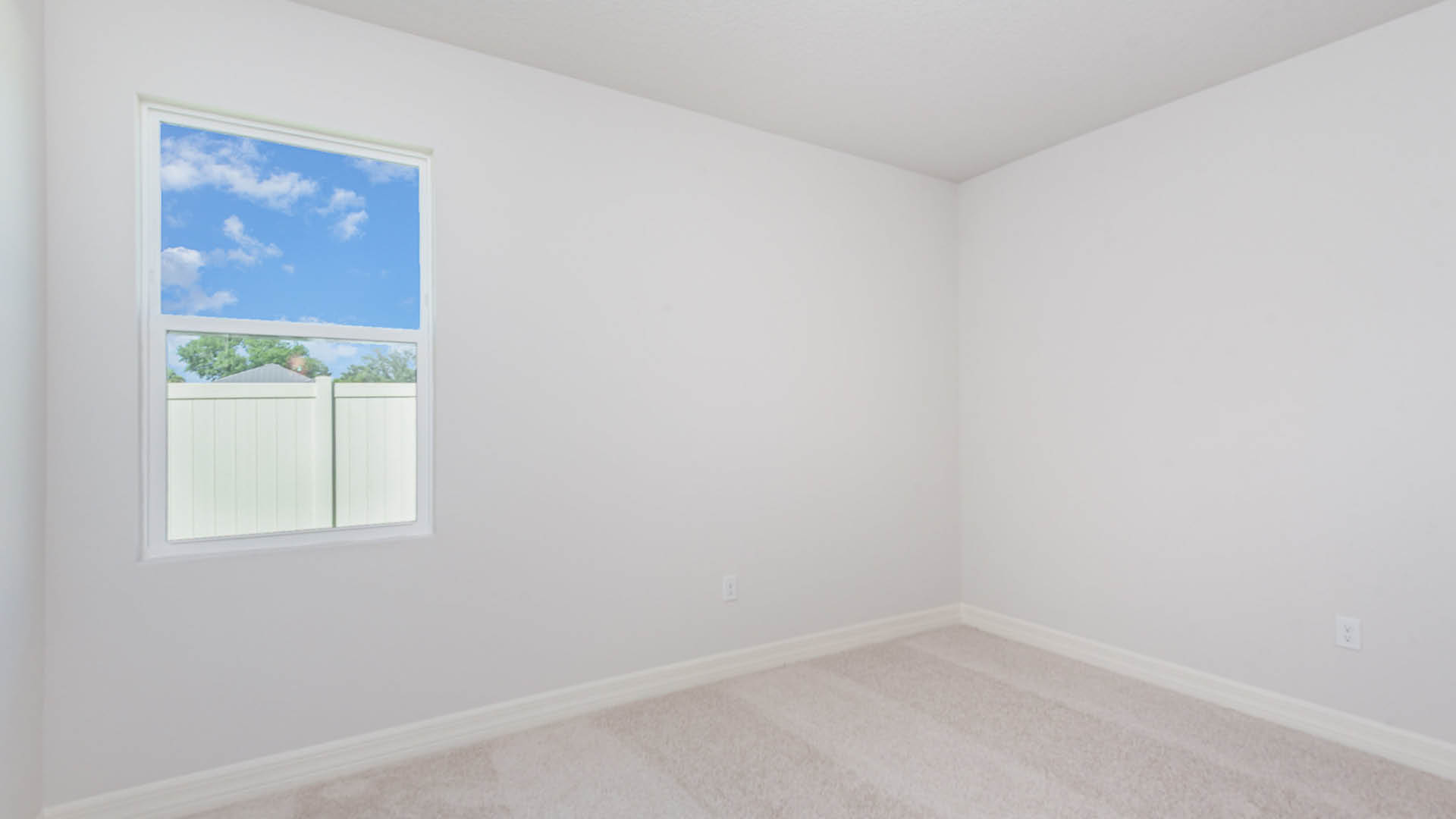 Empty room with white walls and a single window letting in natural light.