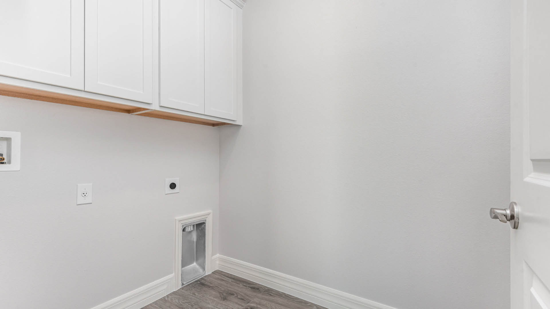 A bright white laundry room featuring a door and a window, creating a clean and airy atmosphere.