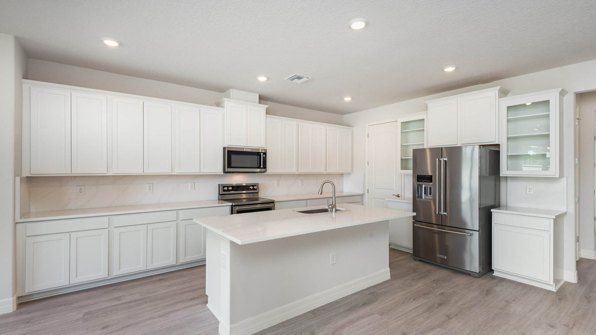 Bright kitchen with sleek white cabinetry and stainless steel appliances, emphasizing cleanliness and contemporary design.