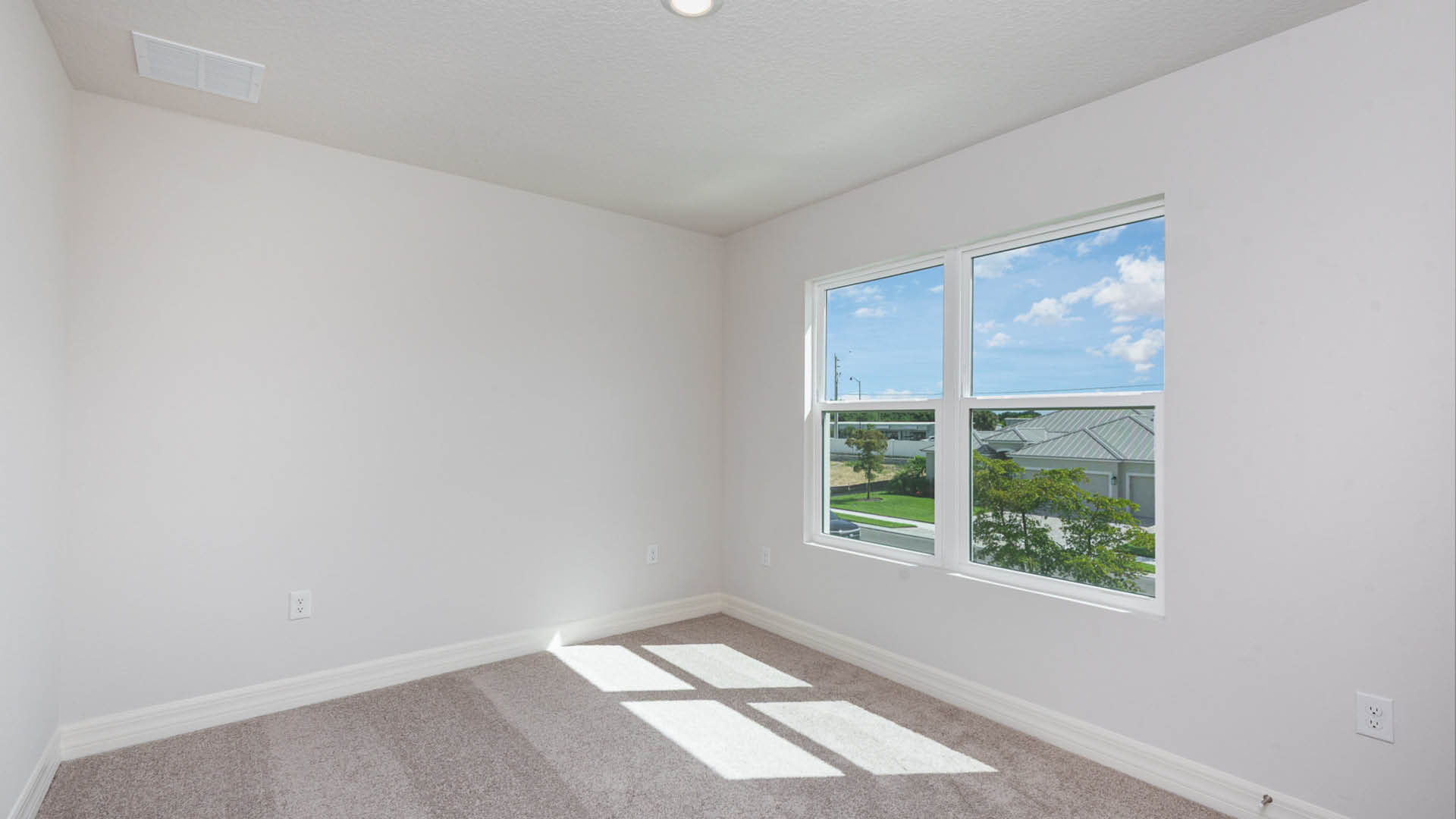 Empty room featuring a window and a carpet, with neutral walls and natural light streaming in.