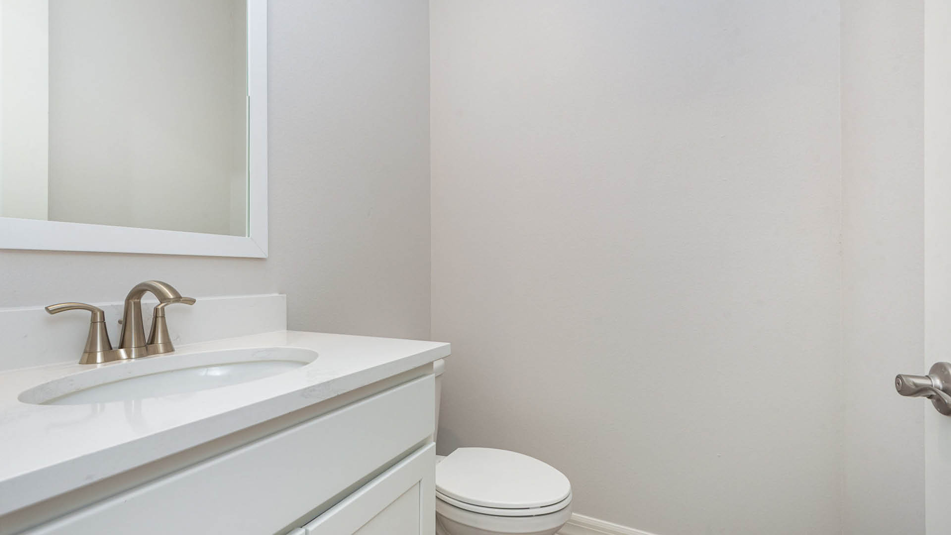 Clean bathroom featuring a white sink and a white toilet against a neutral wall.