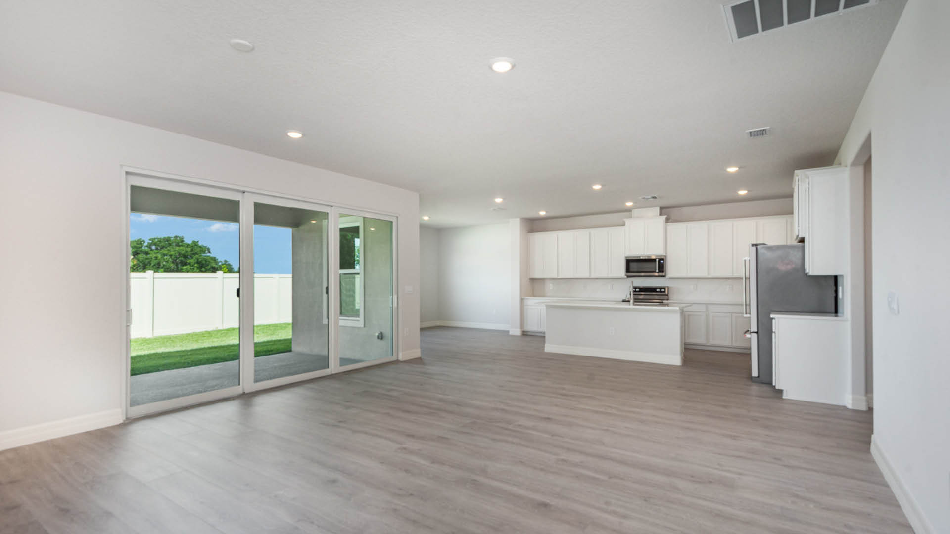 Spacious, empty kitchen featuring sliding glass doors that open to an outdoor area.