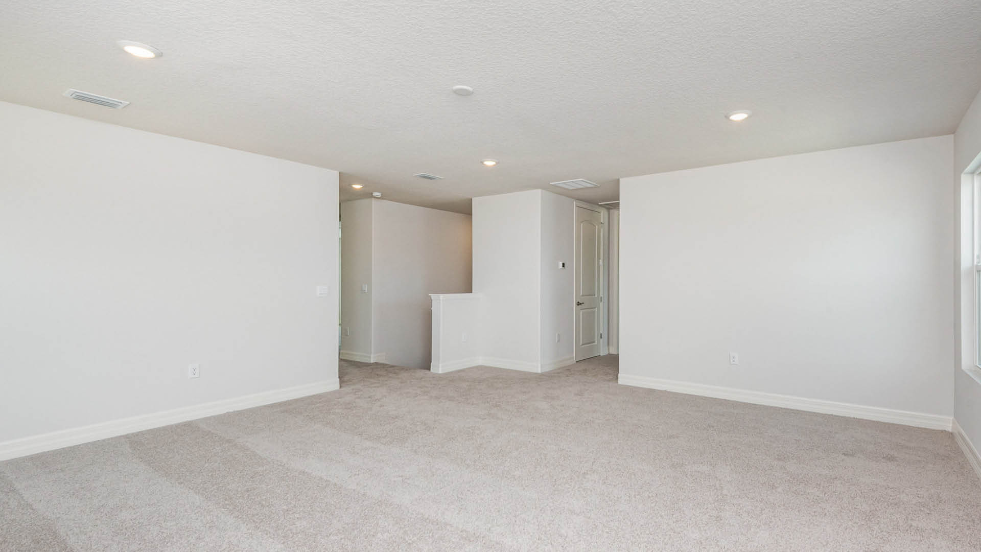 Modern kitchen featuring white cabinets and stainless steel appliances, showcasing a clean and organized space.acant room with soft carpet and clean white walls, emphasizing simplicity and openness in the design.