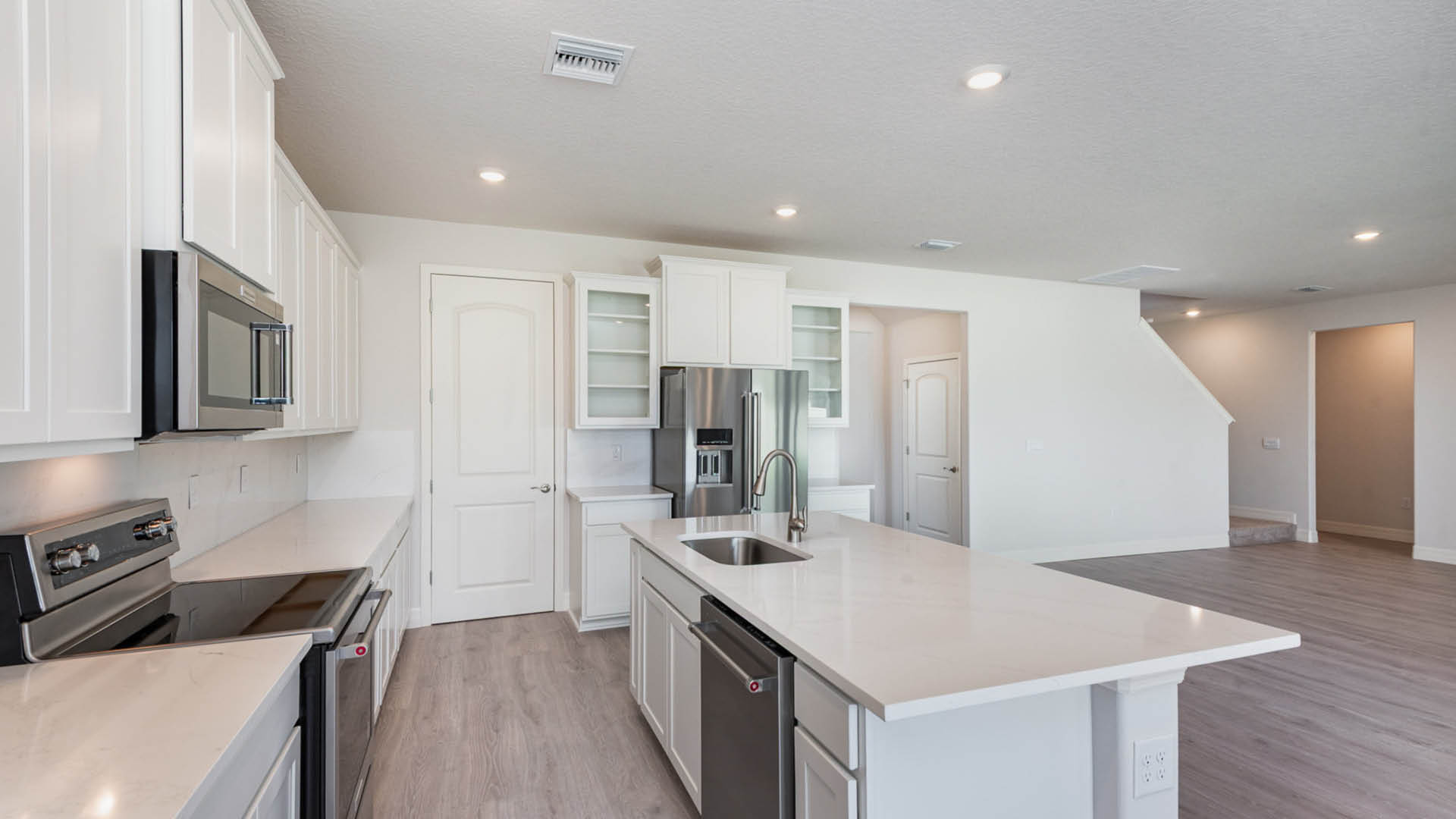 Modern kitchen featuring white cabinets and stainless steel appliances, showcasing a clean and organized space.