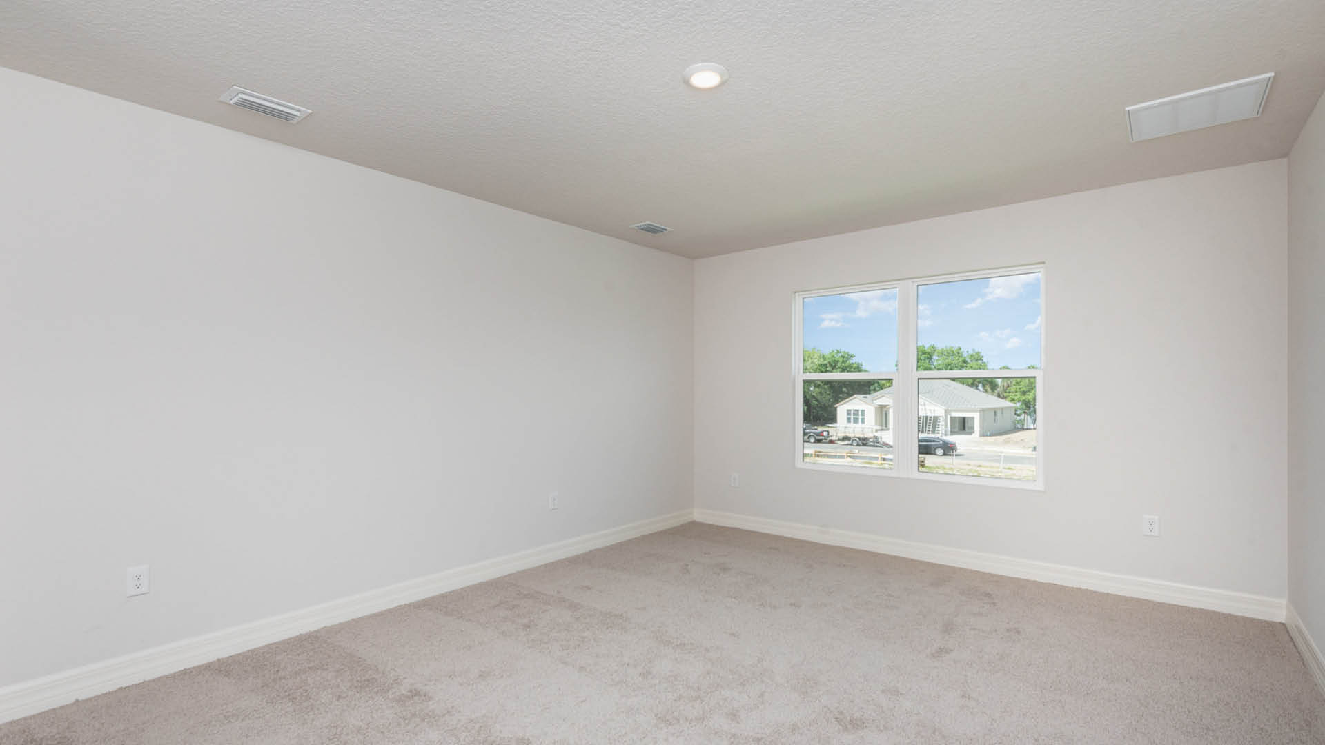 Vacant room with a window and a soft carpet, illuminated by sunlight, creating a serene atmosphere.