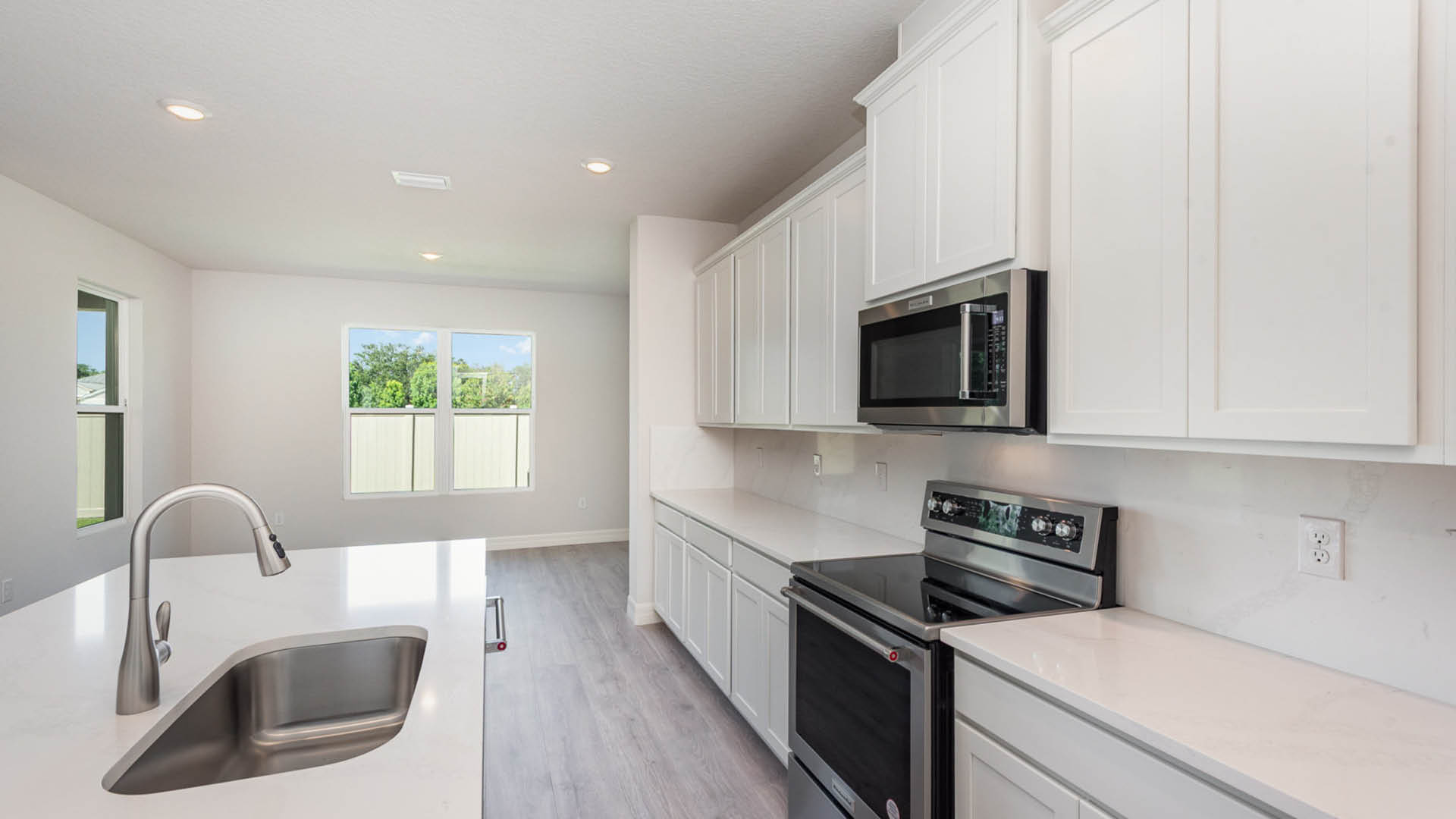 Modern kitchen featuring stainless steel appliances and sleek white cabinets with quartz countertops.