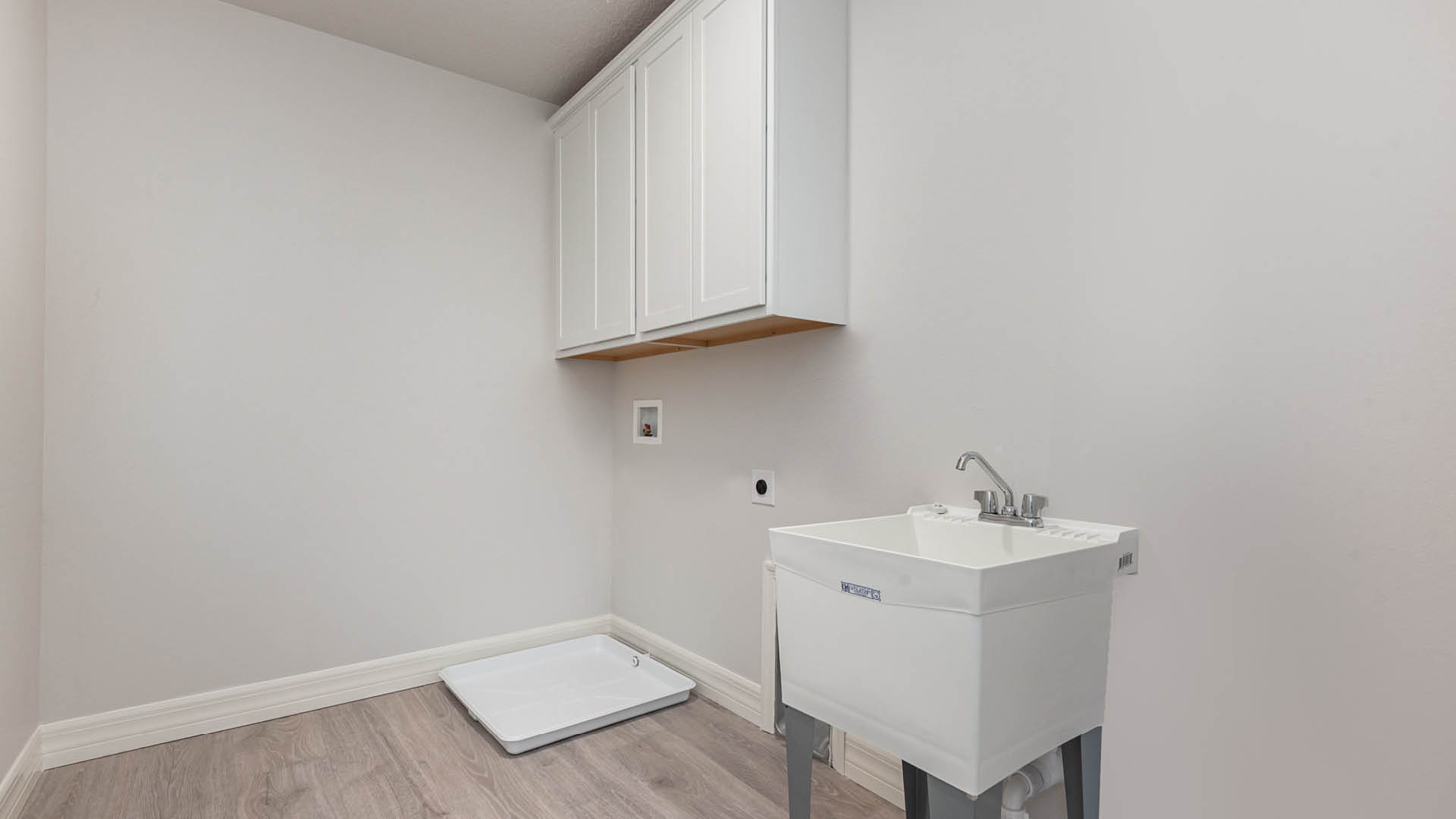 Clean white laundry room with utility sink and vinyl plank floors.