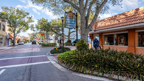 A charming street view in Cocoa, Florida, featuring shops, trees, and directional signs.