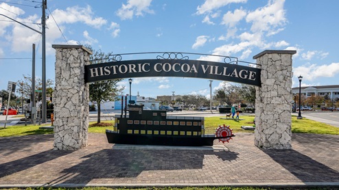 "Welcome sign for Historic Cocoa Village featuring a decorative boat sculpture.