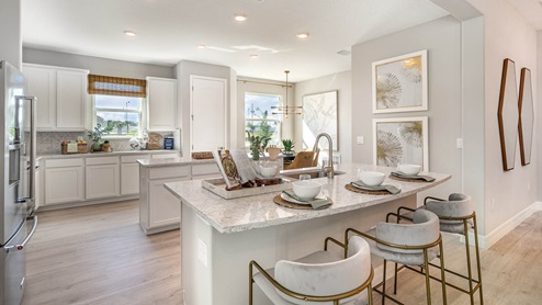 Bright kitchen flooded with natural light from two large windows. White cabinetry, quartz countertops and stainless steel appliances.
