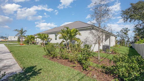 Back of modern single-story home with tropical landscaping.