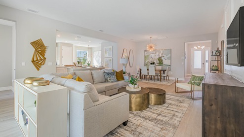 An open floorplan of living, dining and kitchen area with vinyl plank flooring, neutral decor and view of front entry.