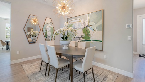 A bright dining area with brown table and white chairs. Large picture and mirrors enhancing the space.