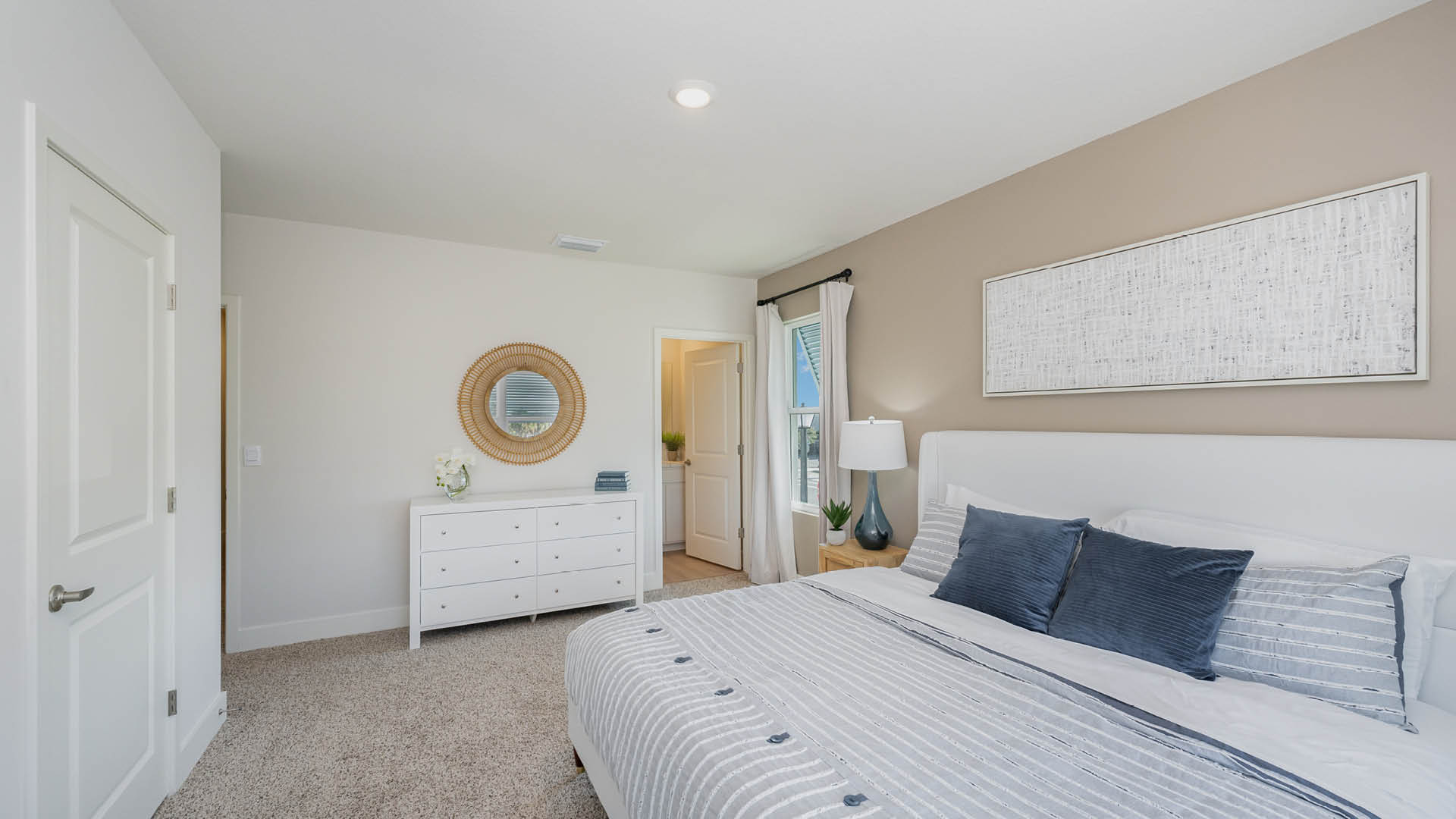 Bright and modern bedroom featuring a white bed, two lamps, and large windows with shades, overlooking a serene outdoor view.