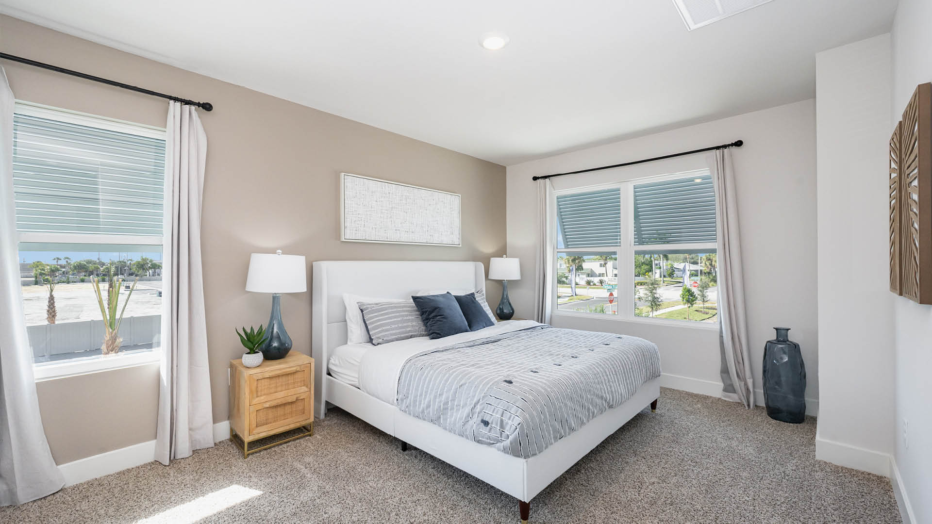Bright and modern bedroom featuring a white bed, two lamps, and large windows with shades.