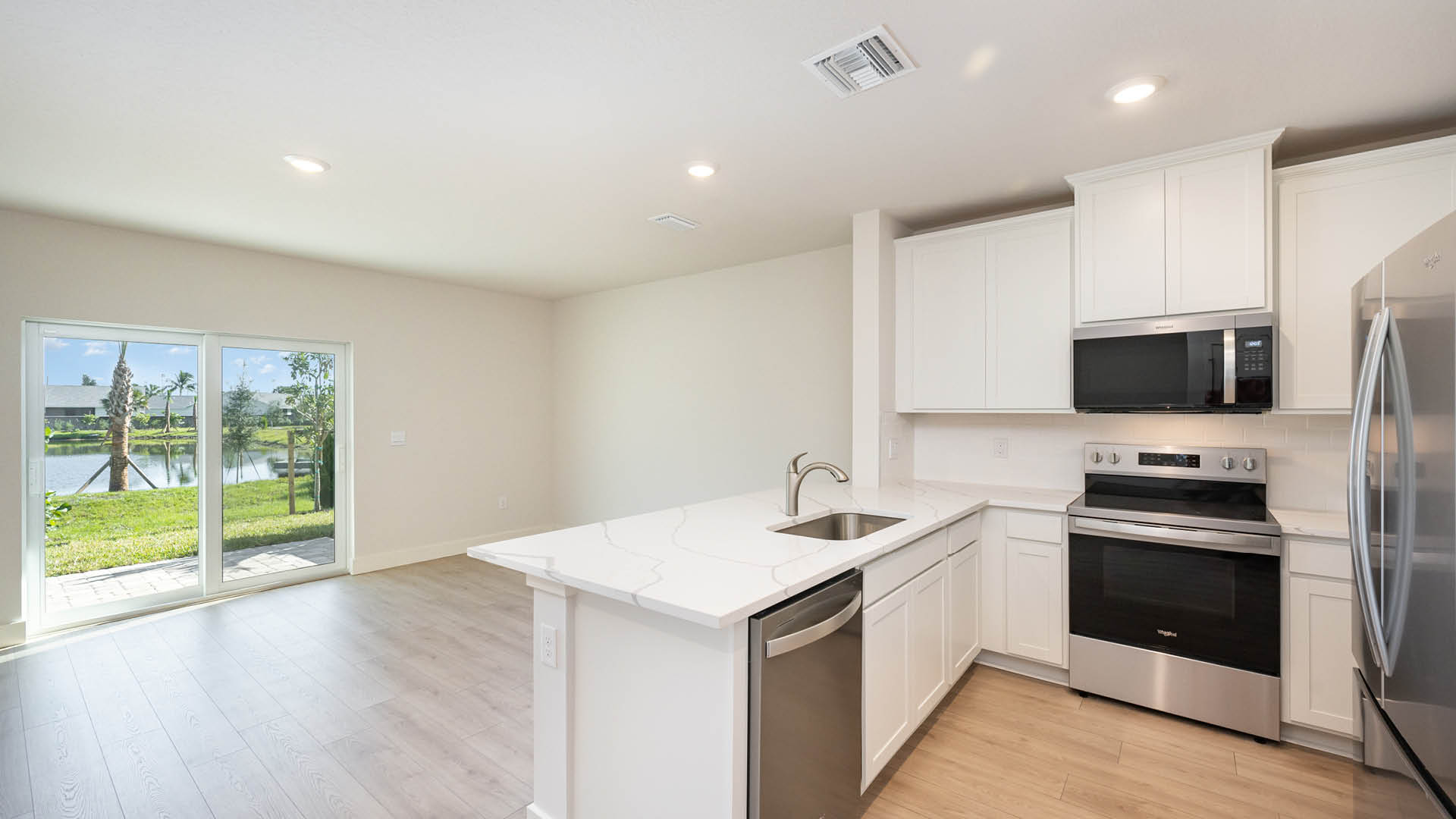 View from kitchen into open concept living room with large sliding glass door leading to the patio.