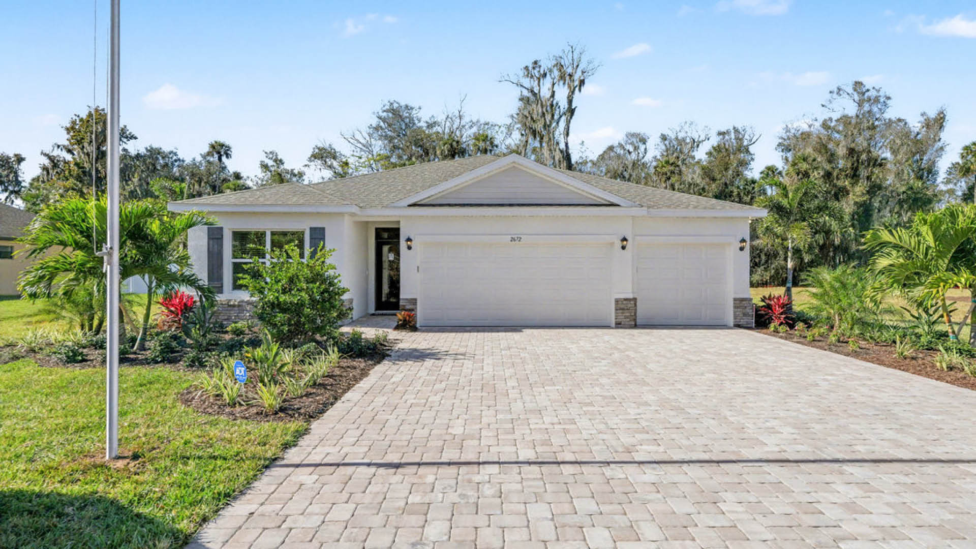 Single-story Home with stone accents, 3-car garage and paver driveway.
