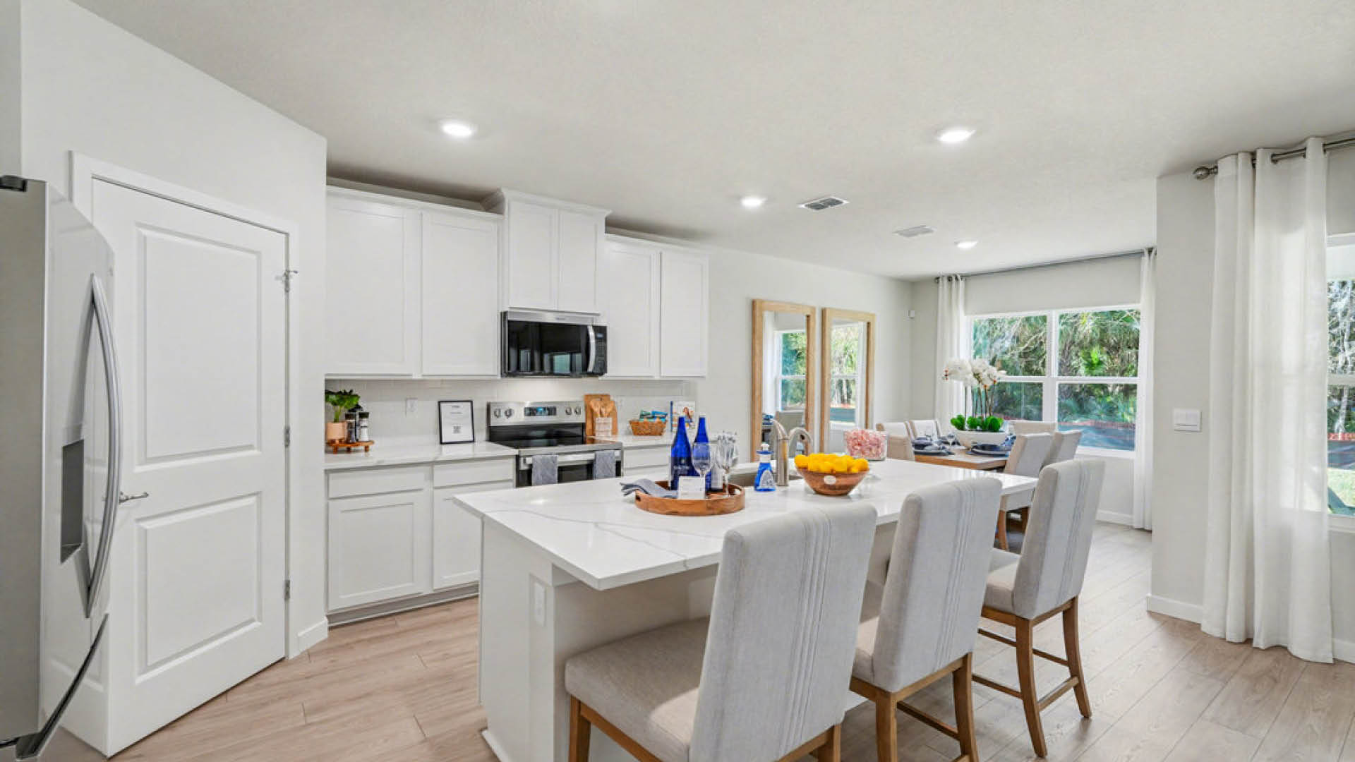 Modern kitchen featuring white cabinets, an island with seating, stainless appliances, and large windows for natural light.
