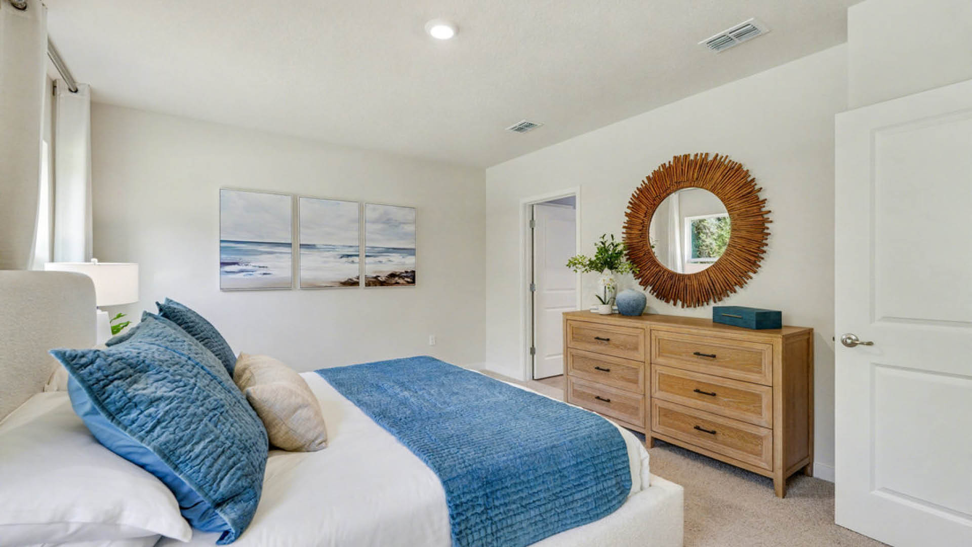 A cozy bedroom featuring a blue bed and a white dresser against a neutral wall.