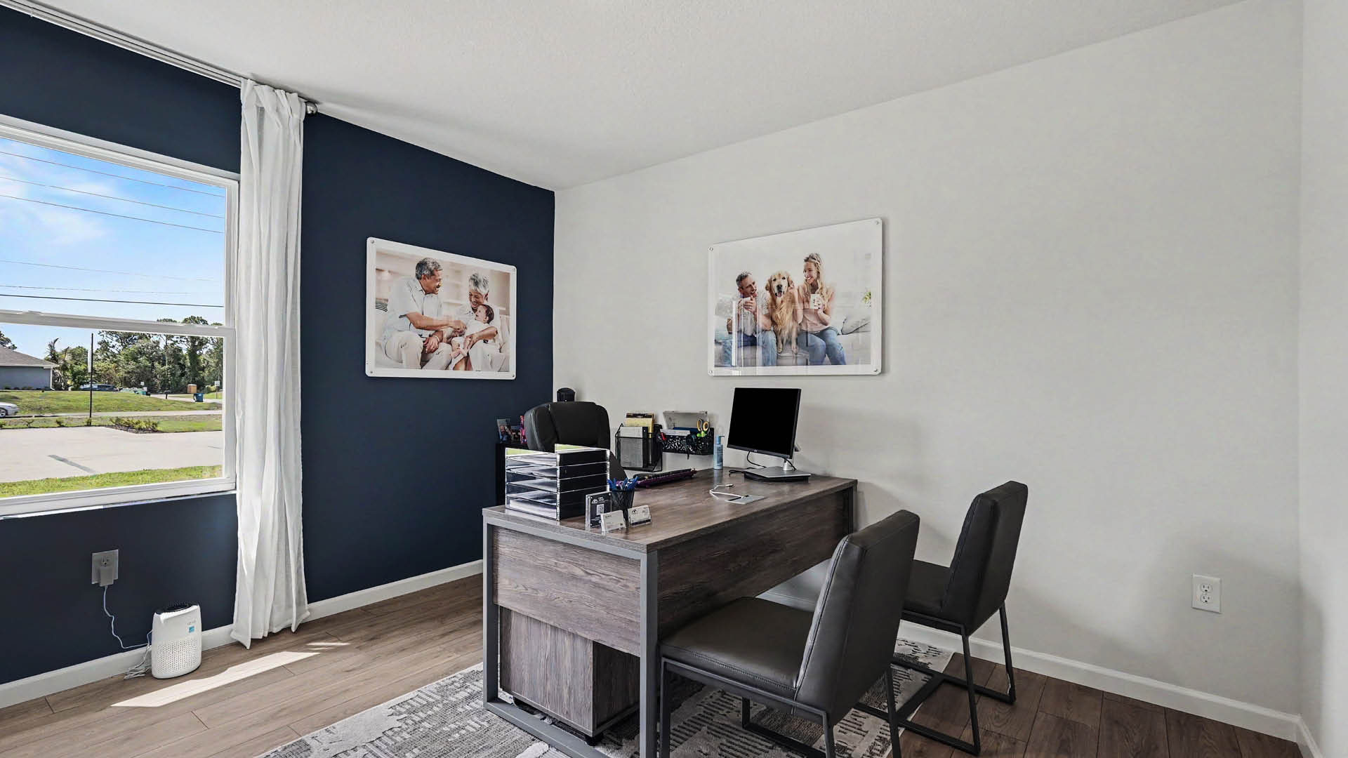 A room furnished as an office with a large window and Mohawk® Revwood Select Plank Flooring.