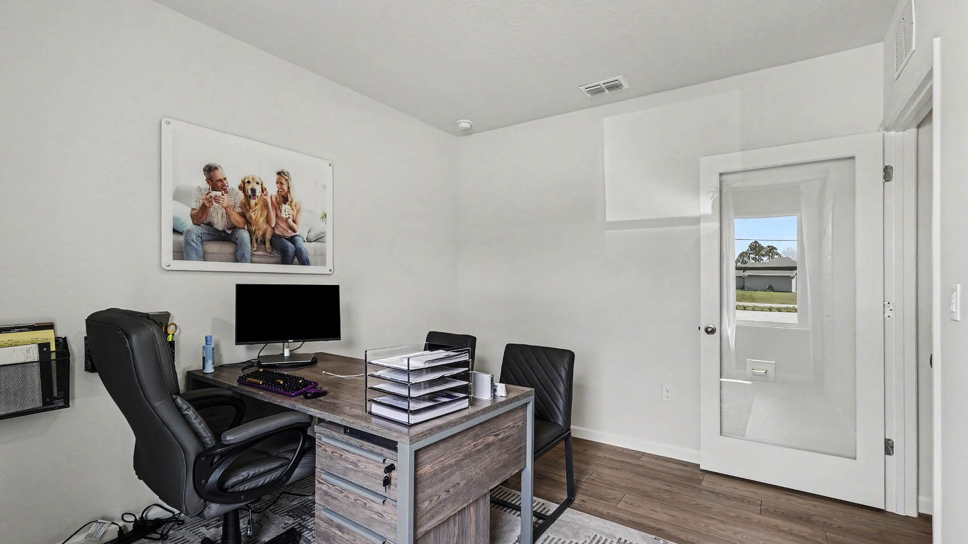 A room furnished as an office with a large window and Mohawk® Revwood Select Plank Flooring.