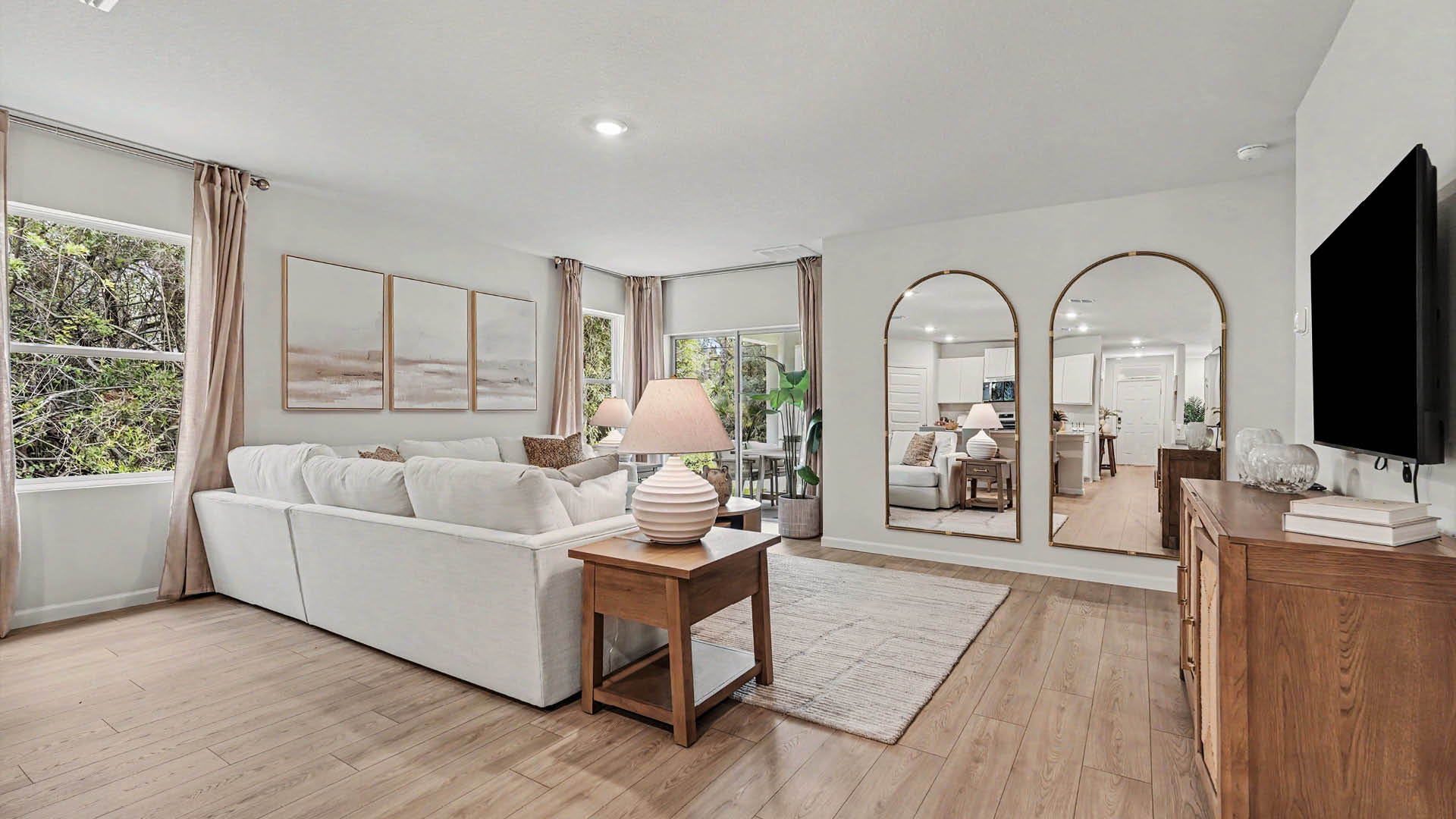 A spacious living room area with Mohawk® Revwood Select Plank Flooring throughout.  Sliding glass doors leading out to a covered lanai are visible.