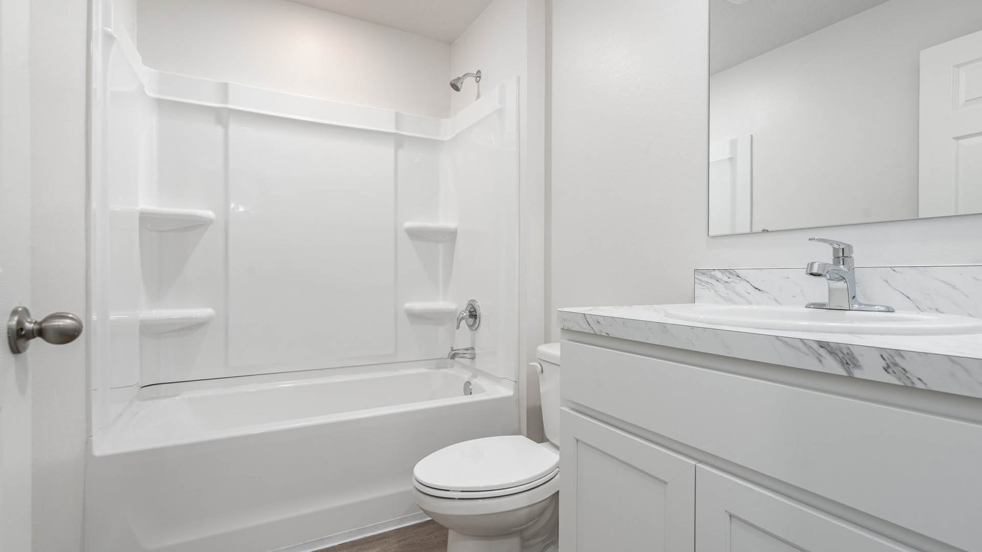 A clean, modern bathroom featuring a bathtub with a shower and a large mirror against neutral-colored walls.