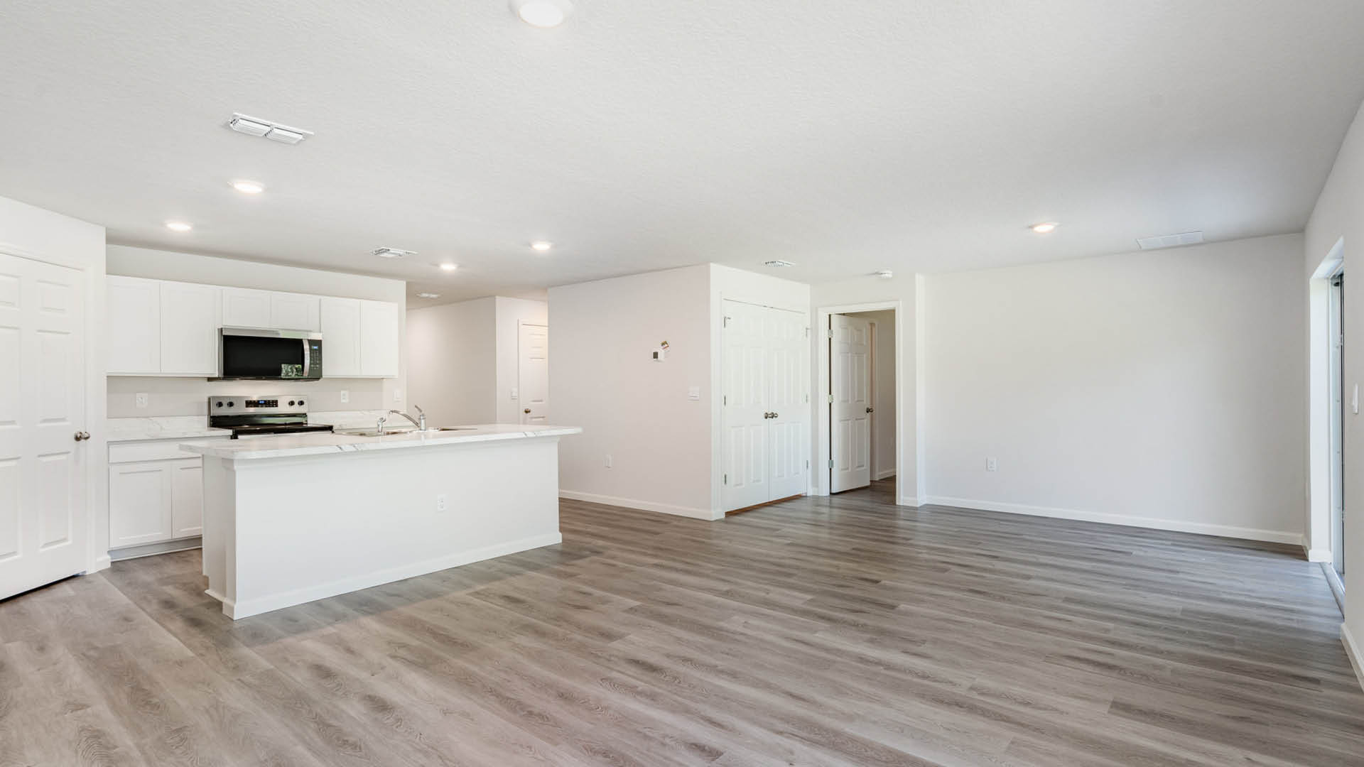 A cozy dining area with large windows leading into a modern kitchen with white cabinetry, stainless steel appliances, and a large island with seating.