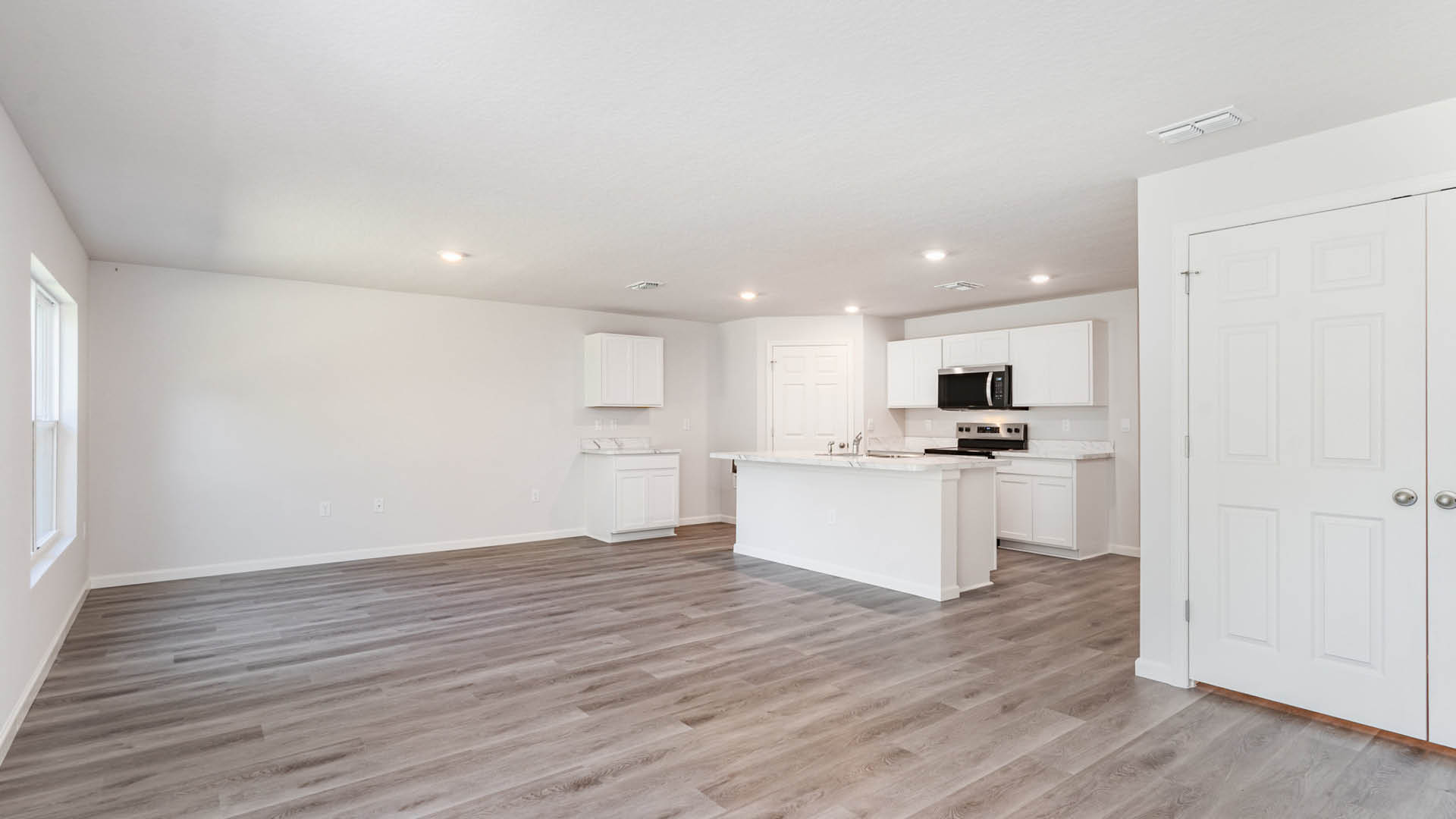 A spacious living room, leading into a dining and kitchen area.