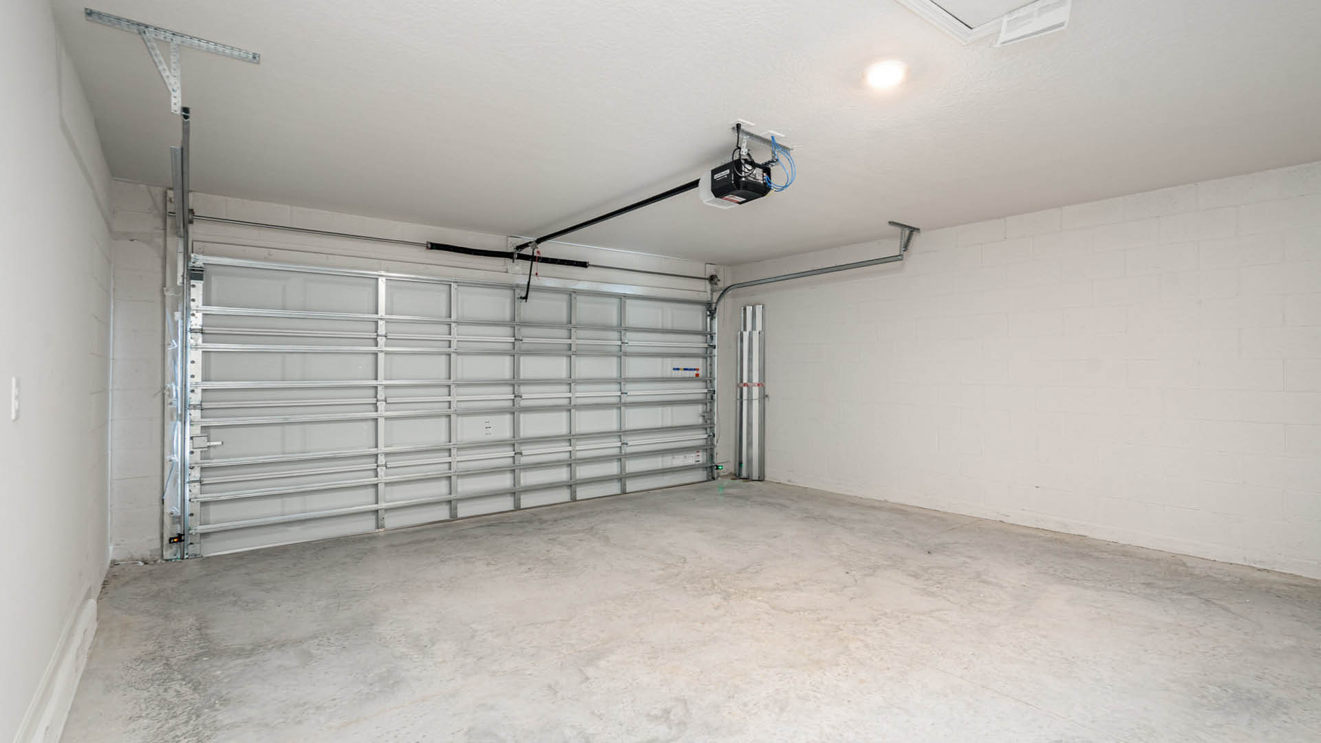 A clean, spacious garage with a light-colored block wall and an automatic garage door opener mounted overhead.