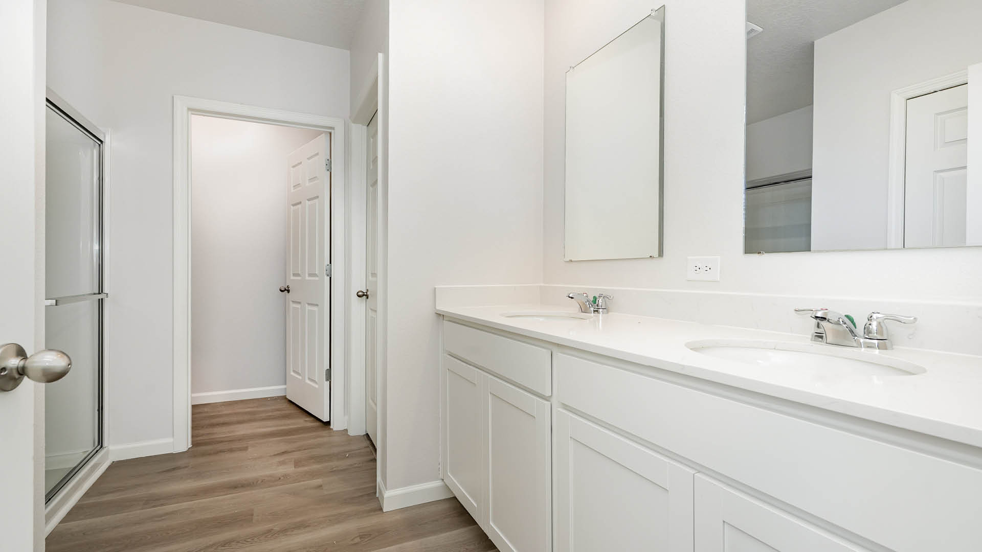 A spacious, modern bathroom featuring a glass, walk-in shower, double sink vanity, and bright lighting.