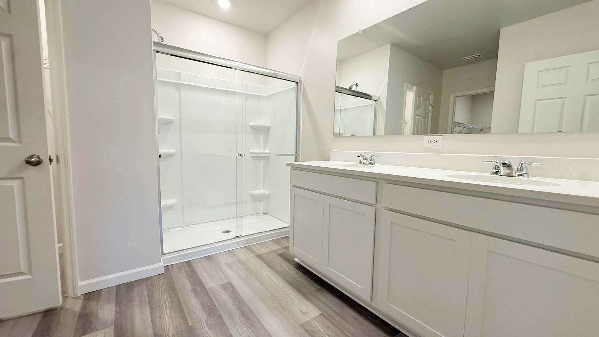 A bathroom featuring a shower and a two sinks, with modern fixtures and neutral-colored tiles.