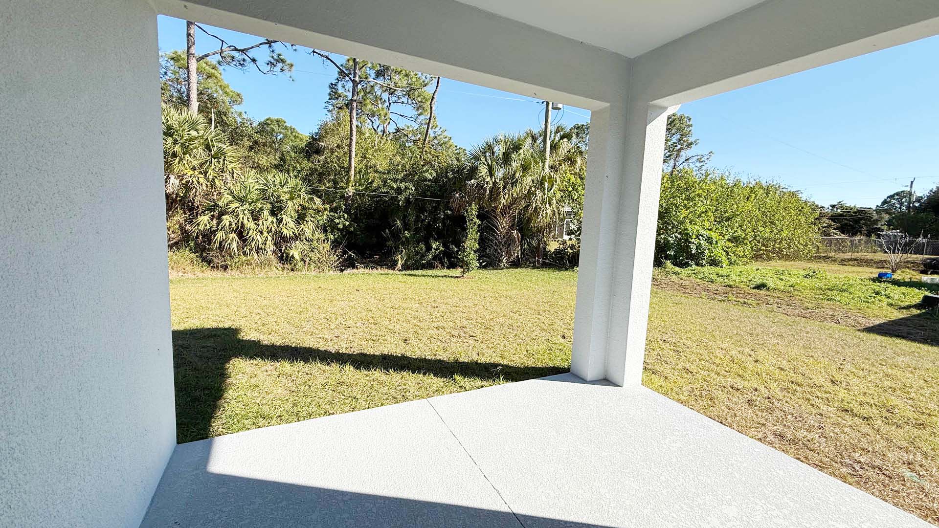 A porch overlooking a lush green lawn and trees, creating a serene outdoor atmosphere.
