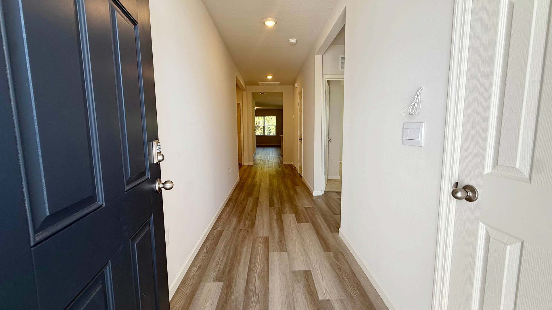 Blue front door open looking down a long hallway with LVP flooring.