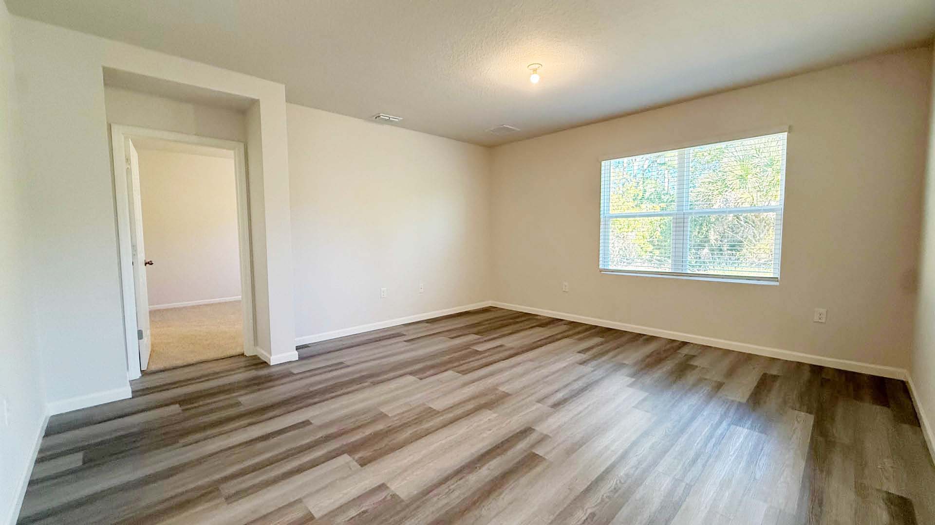 Primary bedroom with LVP flooring and large bedroom window.